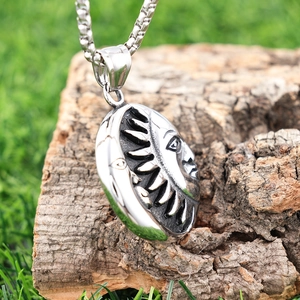 Macro detail of sun and moon relief on a vintage steel pendant resting on tree bark