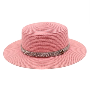Close-up of pink woven boater hat featuring a crystal band and metallic M letter accent