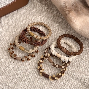 Elegant plush hair ties in milk coffee shades with oval bead accents on textured fabric
