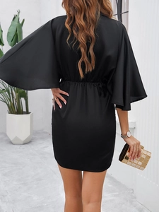 Back view of elegant black batwing sleeve dress with a fitted waist and short hem