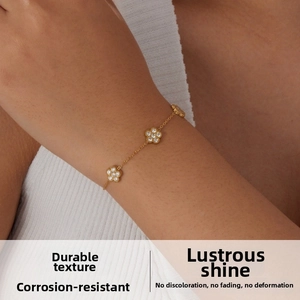 Détail d'un bracelet doré avec des breloques en fleurs de zircon porté au poignet