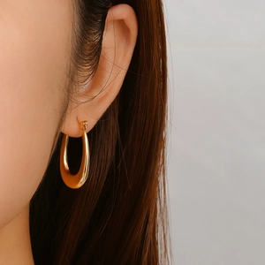 Élégantes boucles d'oreilles créoles ovales plaquées or 18 carats portées par un mannequin