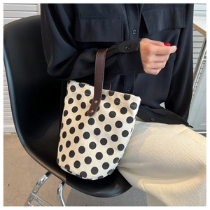 Polka dot canvas bucket bag shown held by a person in a daily lifestyle scene