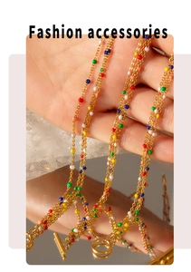Close-up of golden multilayer necklace with colorful enamel beads held in hand
