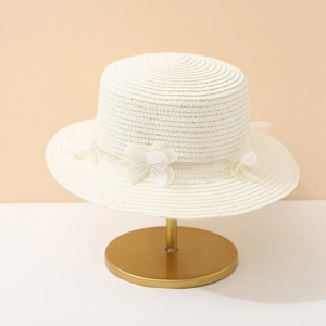 White woven flat top straw sun hat with delicate mesh flower on a golden display stand