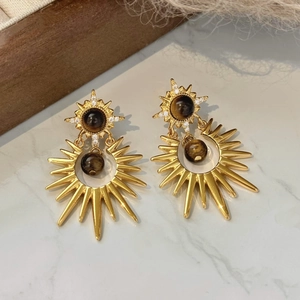 Detailed view of vintage gold sunburst earrings with brown tiger eye stones and zircons