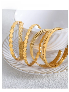 Five-piece set of gold-plated geometric bangles with heart and woven textures in ceramic bowl