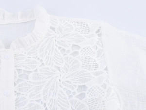Close-up of white lace embroidery details on the front of a ruffled collar blouse