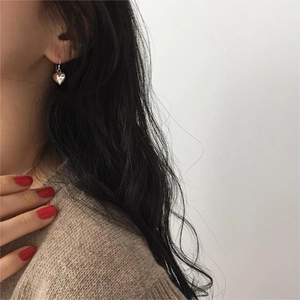 Close-up of minimalist silver heart drop earrings worn by a model in a natural style