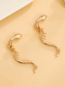 Λεπτομέρεια από χρυσά σκουλαρίκια φίδι με υφή λεπιδιών και πράσινα μάτια από πολύτιμο λίθο