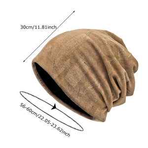 Distressed tan knit beanie with green stitching and sizing details on white background