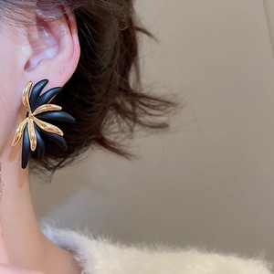 Macro side view of vintage floral 18k gold earrings with black contrast on model