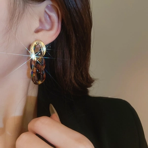 Close-up of leopard print linked chain earrings with golden finish and starburst sparkles