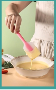 Pink silicone spatula mixing yellow cream in a bowl for DIY cake baking and pastry making