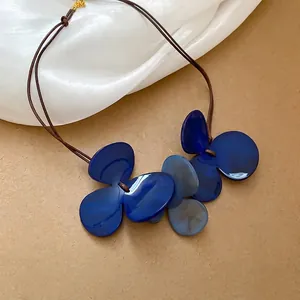 Artistic clover pendant necklace with blue resin petals on brown cord for beach vacation