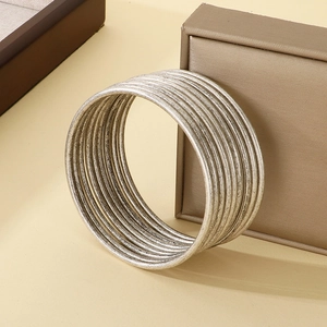 Detail of stacked silver stainless steel bangles with textured finish on jewelry box