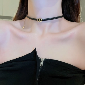 Close-up of braided black leather choker with a gold-tone CD letter metal clasp