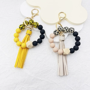 Detail of silicone beaded wristlet keychain with wood bead, leather tassel and gold clasp