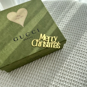Close-up of golden acrylic Merry Christmas cake topper on elegant green gift box