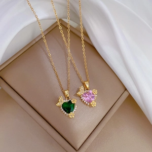 Luxury heart zircon necklaces in green and pink with golden chains on silk background