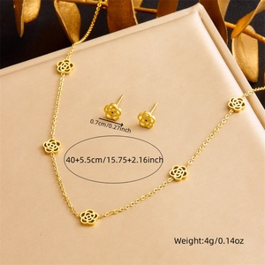 Golden hollow camellia jewelry set with necklace and stud earrings on textured surface