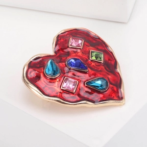 Detail of a gold heart brooch with red enamel and vibrant multi-colored crystals