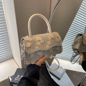 Detail of silver sequin square bag with white handle and elegant reflective surface