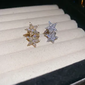 Golden and silver star ear cuffs with zircon pavé on beige velvet display