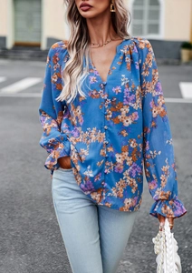 Dettaglio di una camicetta blu a fiori con scollo a V, polsini a balze e bottoni eleganti
