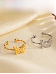 Detail view of gold and silver butterfly rings with rope texture on silk background