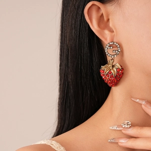 Vintage gold strawberry earrings with rhinestone letter G on a female model