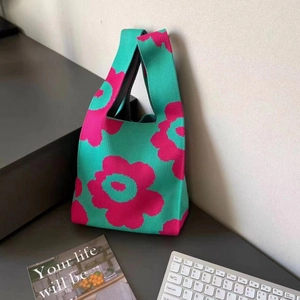 Detail of green and pink knit floral tote bag in a lifestyle desktop setting