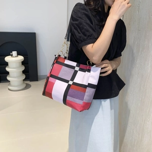 Borsa tote chic con motivo geometrico e catena dorata, mostrata indossata dalla modella