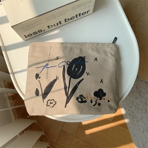 Close-up of beige canvas cosmetic bag with floral embroidery on white table