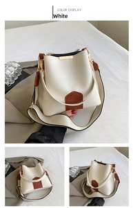 Detail view of white bucket bag with brown trim, fabric strap and golden hardware