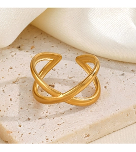 Close-up of golden X-shaped crossover ring on stone base with soft silk background