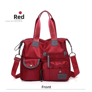 Front detail of red multi-pocket oxford cloth tote bag with wide webbing straps