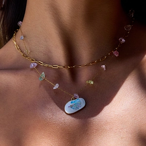 Close-up of double-layer gold necklace with colorful stones and hand-painted fish pendant