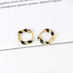 Detailed close-up of gold twist hoop earrings with black enamel finish on white background