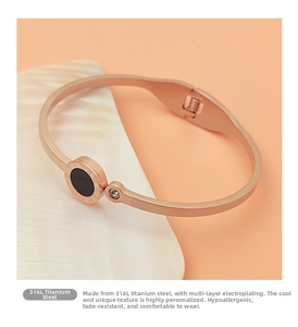 Detailed close-up of rose gold bangle with roman numerals on a white shell prop