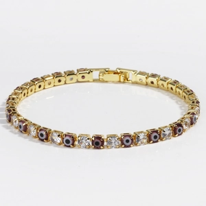 Macro detail of gold tennis bracelet featuring 4mm zircon and evil eye beads