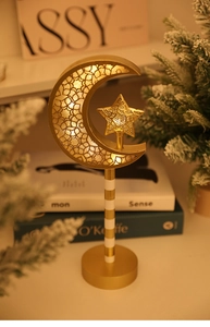 Golden moon and star LED lamp with intricate hollow patterns on a cozy home desk