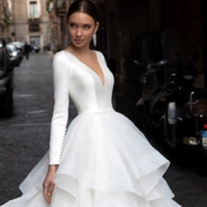 Detail of white deep V-neck wedding dress with long sleeves and layered organza skirt