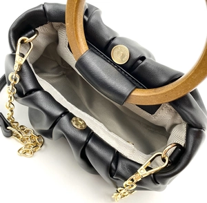 Detail view of cloud bag with wooden handle, gold chain strap, and magnetic clasp