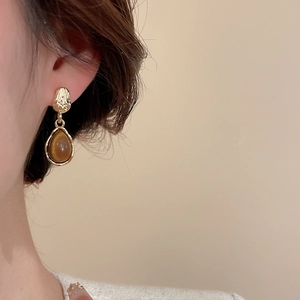 Vue détaillée des boucles d'oreilles goutte en résine avec métal doré et pierre brune
