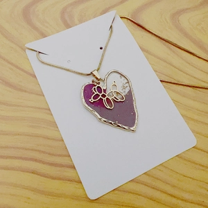 Detail of heart pendant with a gold balloon dog on a fine snake chain necklace