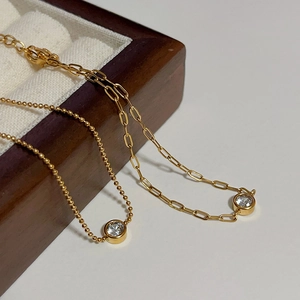 Detailed close-up of 18k gold plated ball chain and paperclip link necklaces with zircons