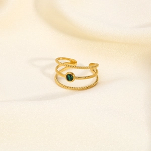 Detail of 18K gold stainless steel triple-layer ring with green gemstone on white silk