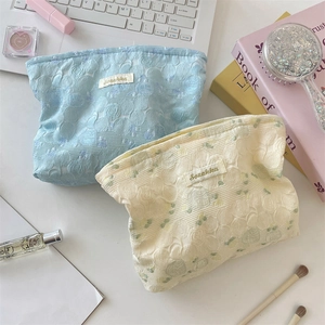 Detail of blue and beige floral jacquard makeup bags set with elegant embossed texture