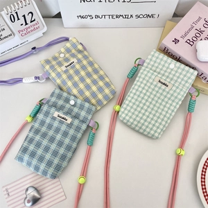 Close-up of stylish plaid crossbody phone bags in yellow, blue and green with snap buttons